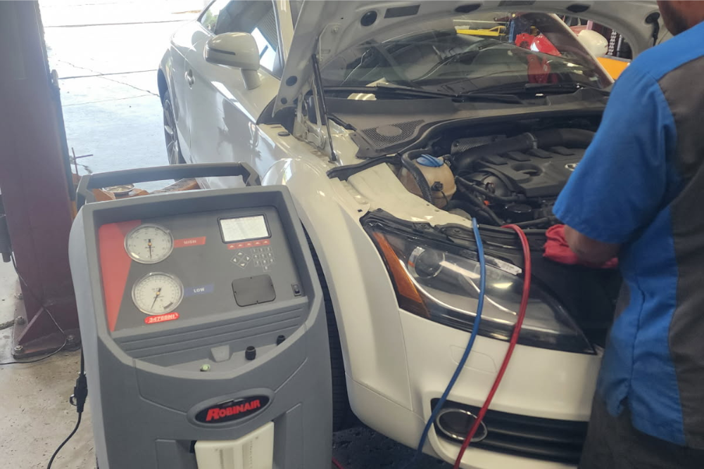 a/c repair, european auto repair in Vacaville, CA at Motoring Specialists. Technician working on a white Audi with hood open and Robinair machine connected for summer A/C maintenance.
