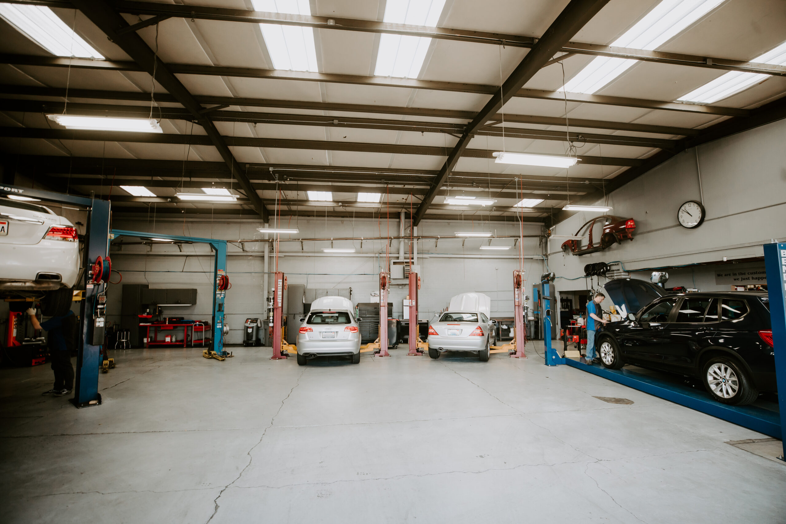 Best European Auto Mechanic in Vacaville, CA at Motoring Specialists. Interior of a clean auto repair shop with multiple cars on lifts and mechanics working on vehicles.
