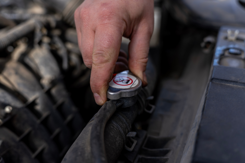 Cooling System Repair in Vacaville CA At Motoring Specialists. Close-up of a technician checking a radiator cap while diagnosing an overheating European vehicle